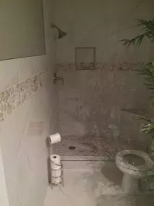 Porcelain tile shower install that ties shower tile with bathroom wainscoating and bathroom floor. 