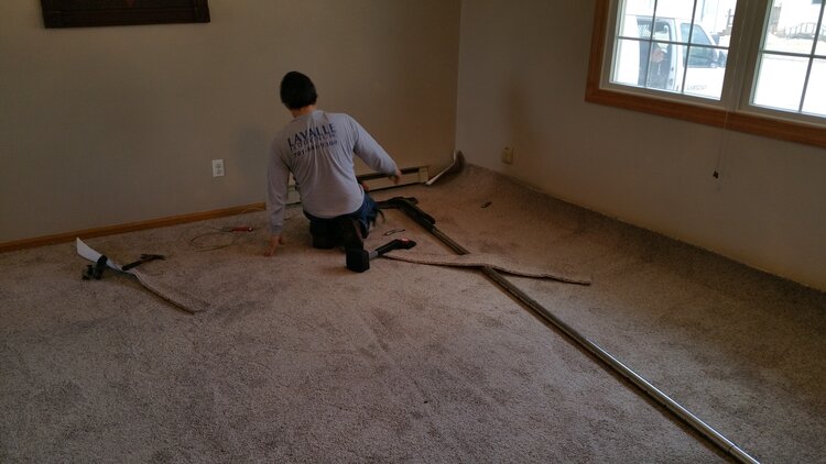 Man installing carpet in living room with power stretcher. 