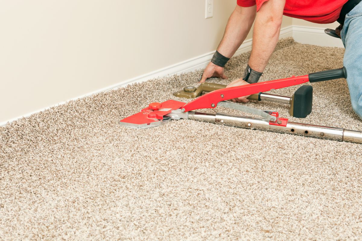 Man installing carpet properly with knee kicker and power stretcher