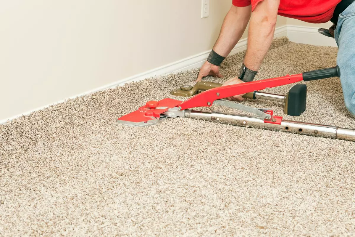 Man installing carpet properly with knee kicker and power stretcher